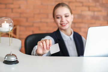 Sticker - Young female receptionist with card at desk in hotel