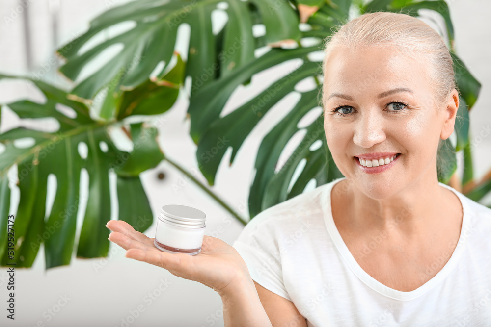Beautiful mature woman with cream at home