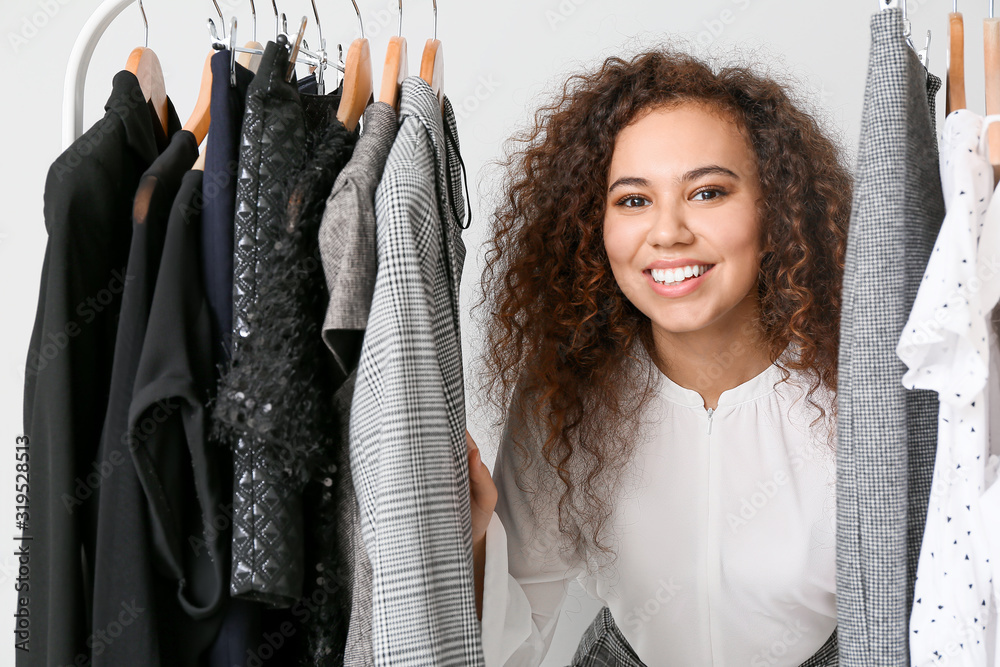 African-American stylist near rack with modern clothes