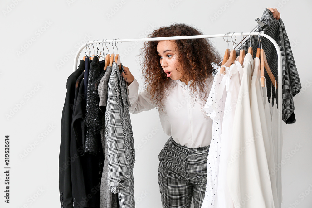 African-American stylist near rack with modern clothes