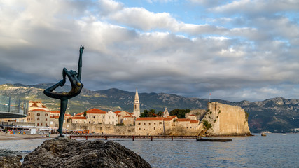 Wall Mural - Ballet Dancer statue against the Old Town of Budva, Montenegro. The statue is the iconic attraction, symbol of the city. 