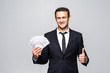 © F8  \ Suport Ukraine - Confident young business man holding dollars banknotes in classic suit shirt tie posing isolated on grey background.