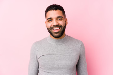 Young latin man against a pink background isolated happy, smiling and cheerful.