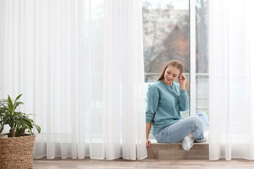 Wall Mural - Beautiful young woman near window at home