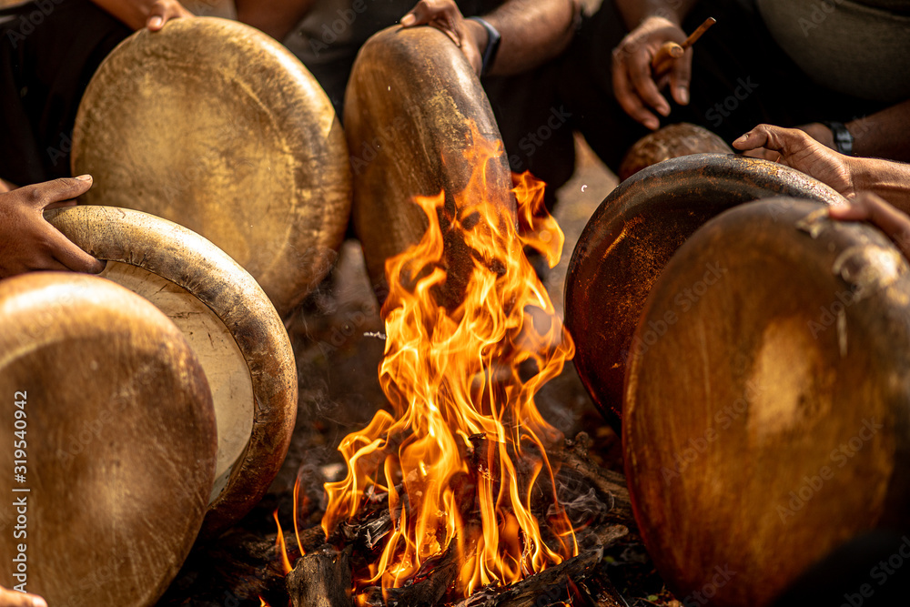 Tamil folk musical instrument "Parai"being tuned with heat from a makeshift bonfire by a team of performers just before staging their musical performance Stock Photo | Adobe Stock