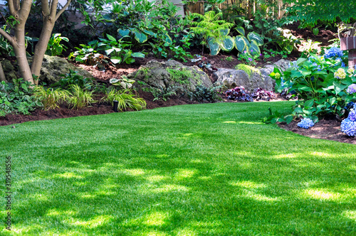Fotomural This beautiful backyard woodland garden features a maintenance free lawn made of natural looking artificial grass, a huge landscaping trend for small spaces