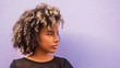 © Camilorico_graphy - Mujer joven afrodecendiente cabello risado suelto mirando hacia un lado sobre fondo morado