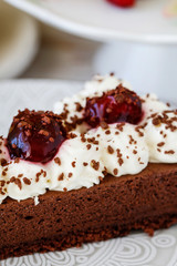 Canvas Print - Chocolate cake with whipped cream decorated with cherries in a sweet sauce.