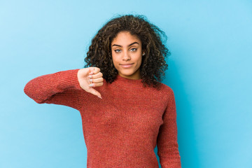 Wall Mural - Young african american curly hair woman showing a dislike gesture, thumbs down. Disagreement concept.