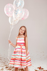 Wall Mural - Inclusive Beauty. Girl with freckles in dress standing isolated on grey holding balloons posing smiling joyful