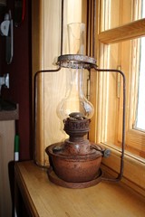 An old kerosene lamp stands on a windowsill in a village house