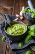 Homemade fresh basil pesto sauce in a bowl, decorated with leaves, garlic and mortar