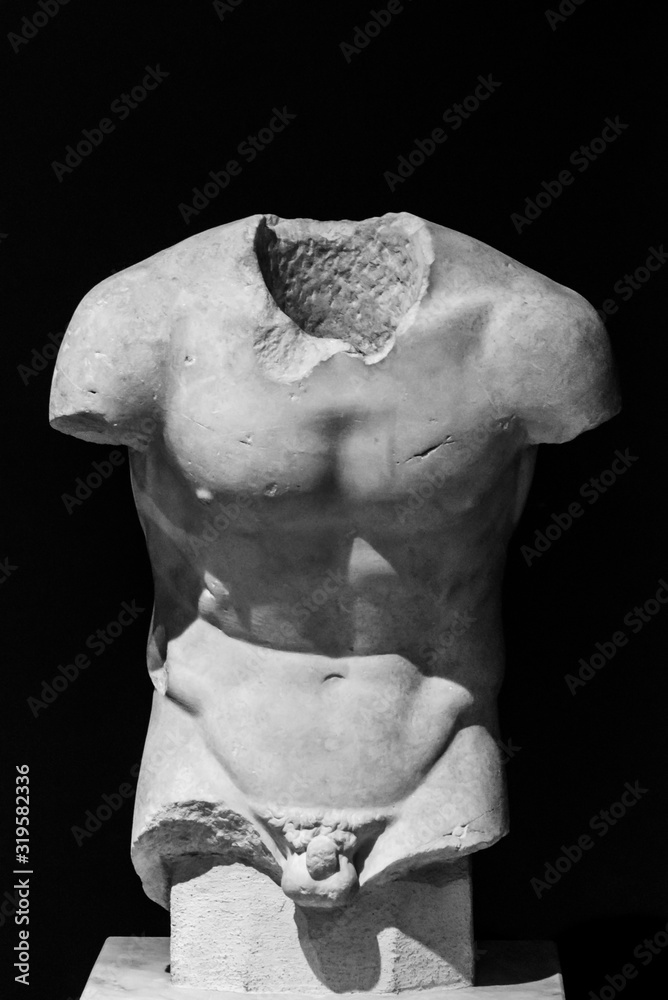 Classical roman sculpture in ruins without head and arms showing athletic male torso - black and white photo - obrazy, fototapety, plakaty 