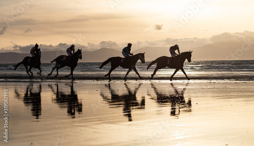 Fotomural Silhouettes of race horses and jockeys racing on the beach, wild Atlantic way on