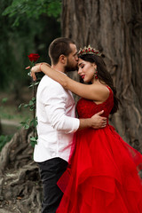 Wall Mural - Beautiful romantic couple kiss closeup. Attractive young woman in red dress and crown with handsome man in white shirt are in love. Happy Saint Valentine's Day. Pregnant and wedding concept.