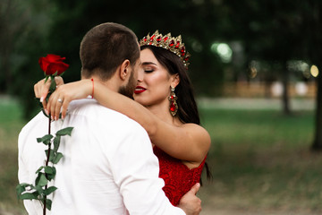 Wall Mural - Beautiful romantic couple kiss closeup. Attractive young woman in red dress and crown with handsome man in white shirt are in love. Happy Saint Valentine's Day. Pregnant and wedding concept.