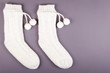 White socks with pom poms on gray background composition.