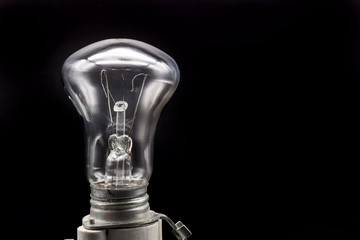 Incandescent lamp on a black background. Light bulb with a torn filament. Old faulty lamp. The concept of an energy crisis. Advertising concept and advertising idea.