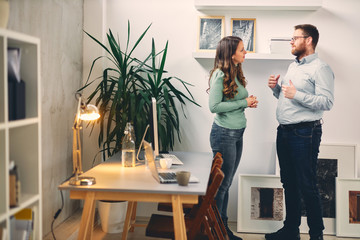 Two coworkers standing in office.