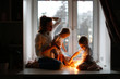 mother with two children at window, evening mood