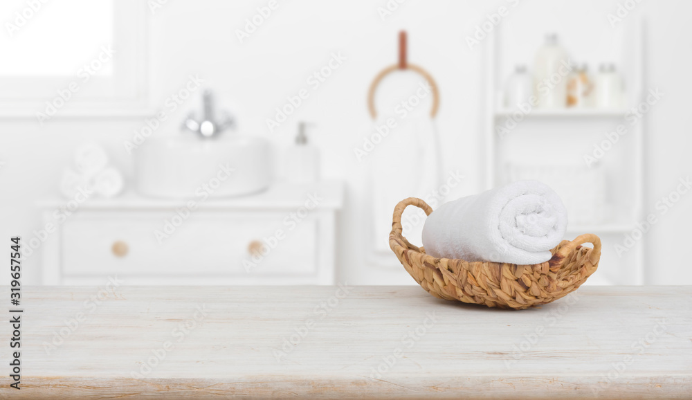 Towel in basket on wooden table over blurred bathroom background - obrazy, fototapety, plakaty 