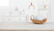 canvas print picture - Towel in basket on wooden table over blurred bathroom background