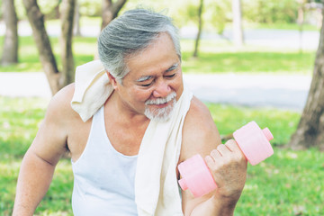  Cheerful elderly Asian man with dumbbell for workout in park, smiling with good healthy