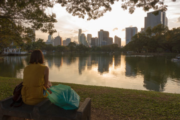 Wall Mural - Woman tourist is finished shopping and watching the view at Lumphini Park in Bangkok.