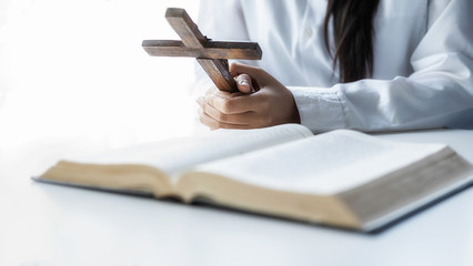 Christian woman praying on holy bible and wooden cross. Woman pray for god blessing to wishing have a better life and believe in goodness.