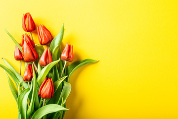 Wall Mural - Yellow background with orange tulips, Easter. Birthday, mother day greeting card concept with copy space. Top view, flat lay.
