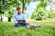 © baranq - Happy young man using tablet while sitting outdoor in the park
