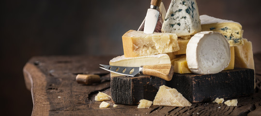 Wall Mural - Assortment of different cheese types on wooden background. Cheese background.