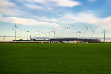 Wind power generators on a green field against a background of blue sky.