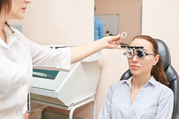 Wall Mural - ophthalmologist doctor in exam optician laboratory with female patient. Eye care medical diagnostic. Eyelid treatment