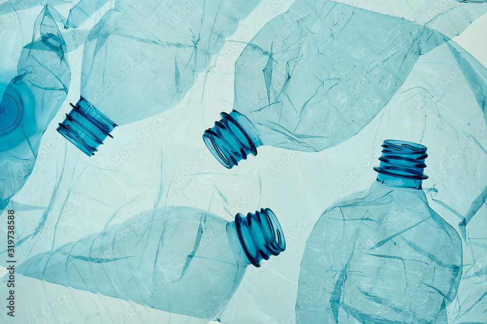 Squashed Plastic Empty plastic squashed bottles over blue background. Collecting plastic ...