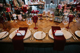 Fototapeta Miasto - Beautiful, decorated table with flower decorations and red candles. Above view, top down. Christmas evening or wedding party decoration.