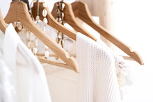 Detail Of White Clothes Hanging On Wooden Hangers In A Fashion Store.
