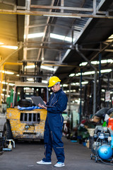 Asian Chief Engineer in the Hard Hat and working on computer laptop about mechanical piece At old Factory Equipment.