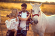 Family of three bonding with a white horse.  Fun on countryside, sunset golden hour. Freedom nature concept.