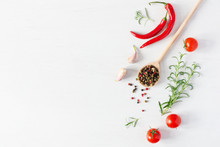 Composition Of Colorful Pepper Seeds, Fresh Chili Pepper, Tomatoes, Garlic And Rosemary Herb Top View On White Wooden Background. Italian Herbs And Spices.