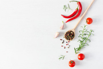 Wall Mural - Composition of colorful pepper seeds, fresh chili pepper, tomatoes, garlic and rosemary herb top view on white wooden background. Italian herbs and spices.