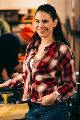 Wall Mural - smiling worker with hand in pocket looking at camera in repair shop