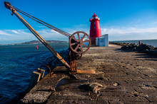 Red Poolbeg Lighthouse With Rusty Crane In Dublin.