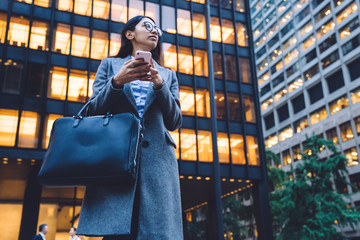 Wall Mural - Ethnic female using smartphone by office building