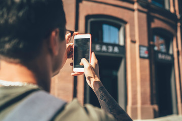 Traveler in casual wear sightseeing while taking photo on smartphone