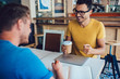© BullRun - Cheerful caucasian brunette businessman having meeting interview with journalist talking to each other smiling, millennial colleagues satisfied with coffee break and friendly conversation on business