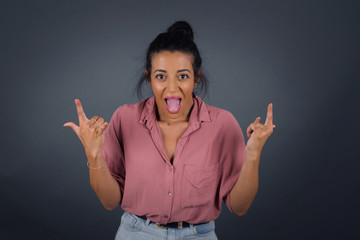 Sticker - Born to rock this world. Joyful woman in fashionable clothes screaming out loud and showing with raised arms horns or rock gesture, expressing excitement of being on concert of band.