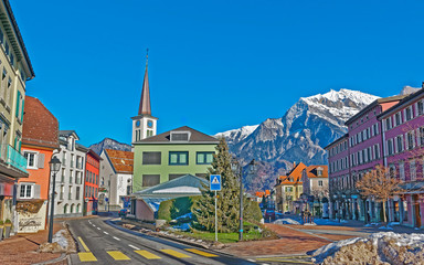 Poster - Catholic Church and Mountains in Town of Bad Ragaz. Bad Ragaz is a city in canton St. Gallen in Switzerland. It lies over Graubunden Alps. Spa and recreation village is at end of Tamina valley