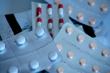 Different packs of medicines in tablet and pills on white surface.