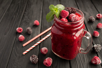 Wall Mural - Smoothies with frozen blackberry and raspberries on the  black wooden background. Closeup.